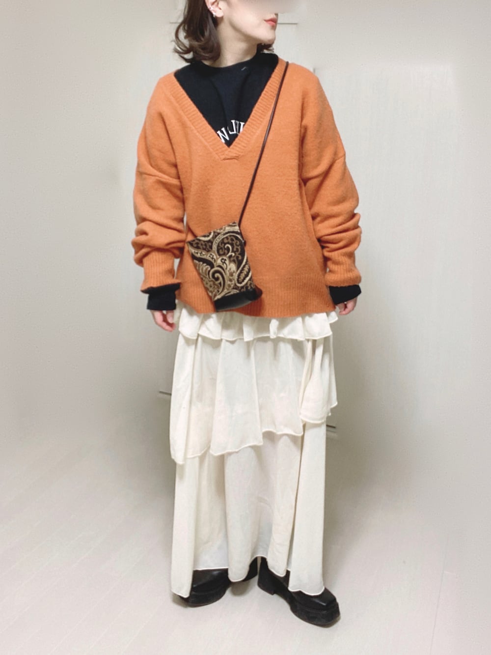 オレンジ系のニット/セーター、ブラック系のスウェット、ブラック系のショルダーバッグを着用したレディースの冬コーディネートの5枚目の写真