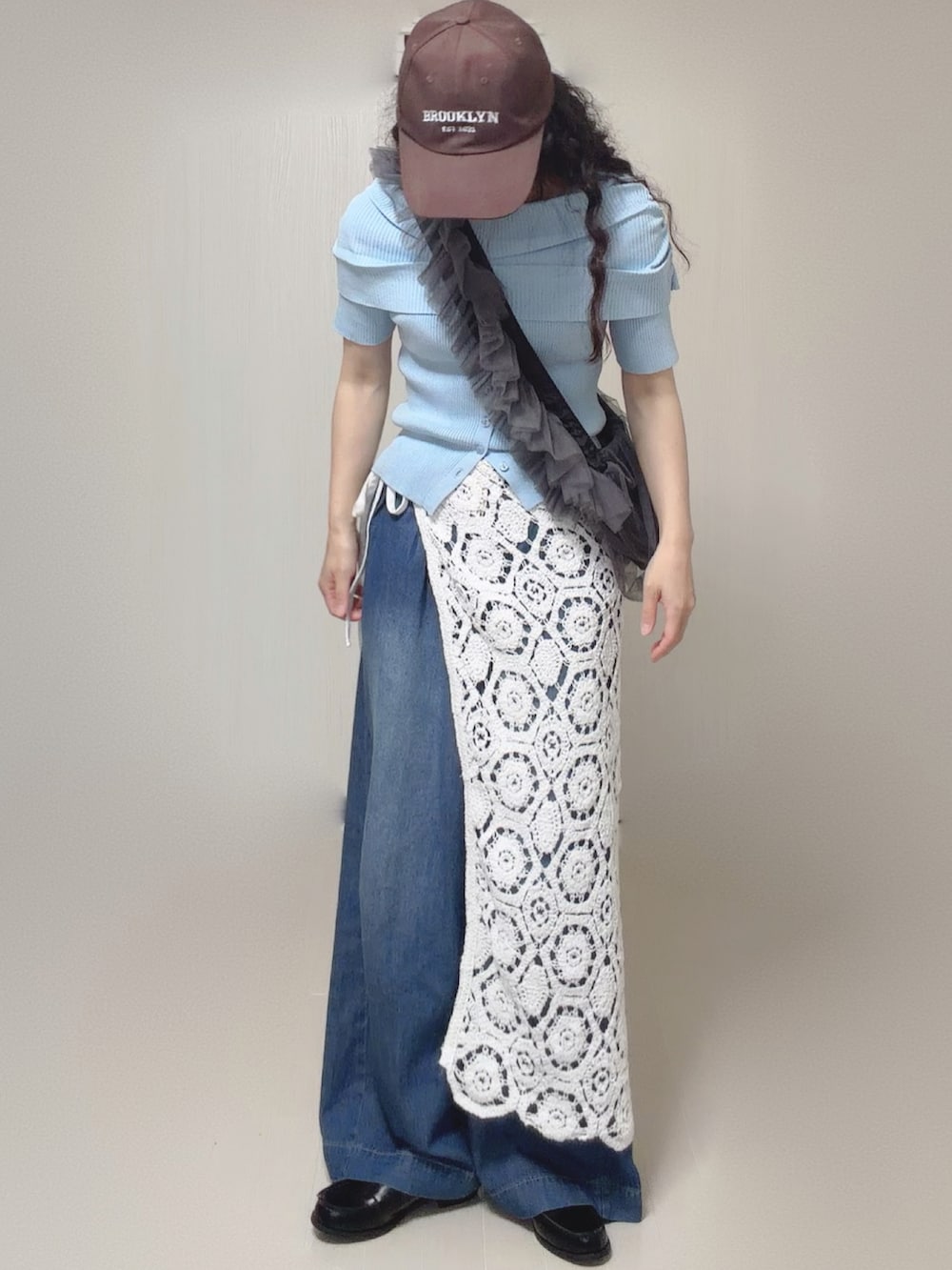 ブルー系のニット/セーター、ホワイト系のスカート、ブルー系のデニムパンツを着用したレディースの夏コーディネートの2枚目の写真