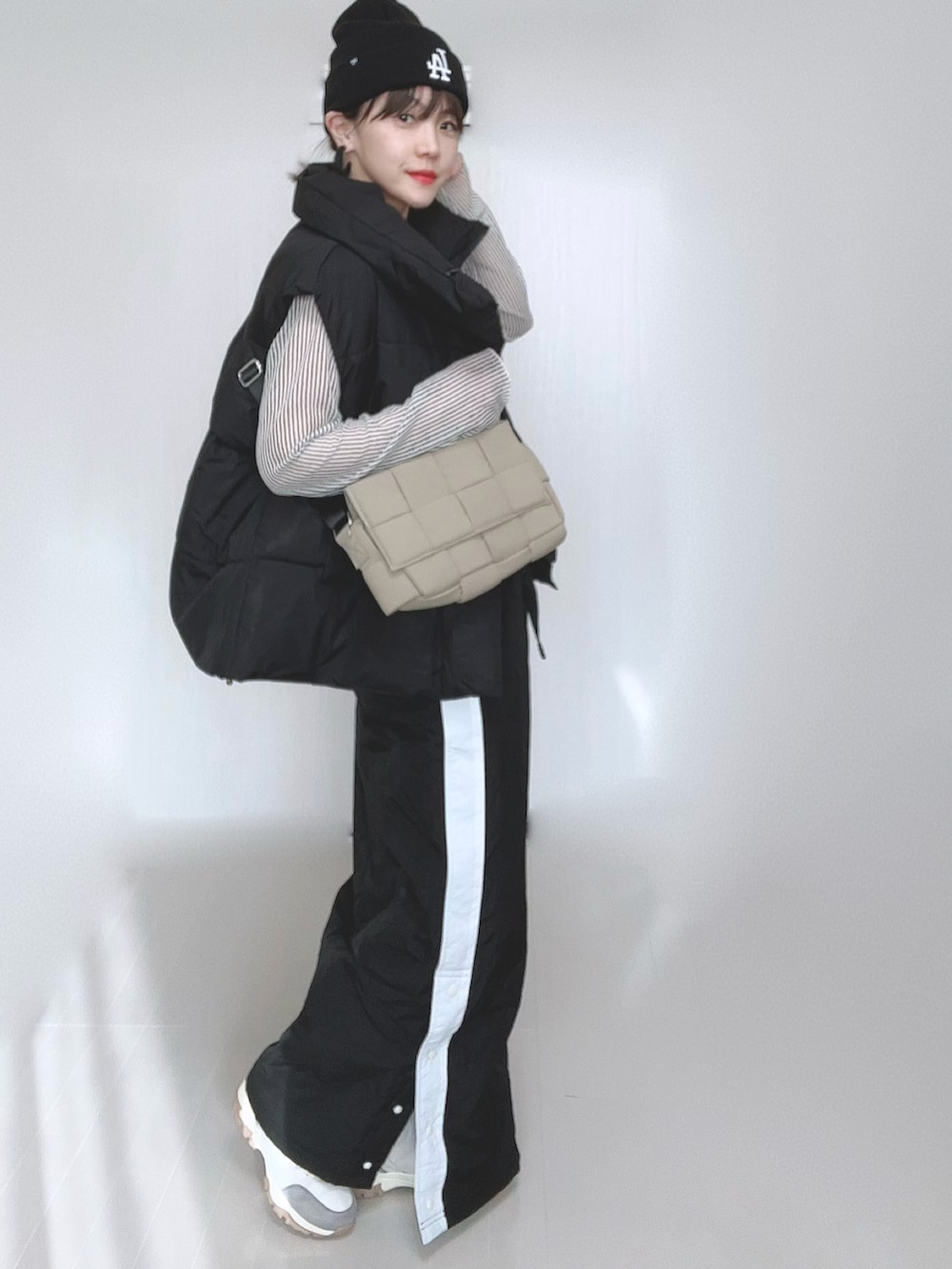 ブラック系のスカート、ブラック系のダウンベスト、ホワイト系のシャツ/ブラウスを着用したレディースの冬コーディネートの3枚目の写真