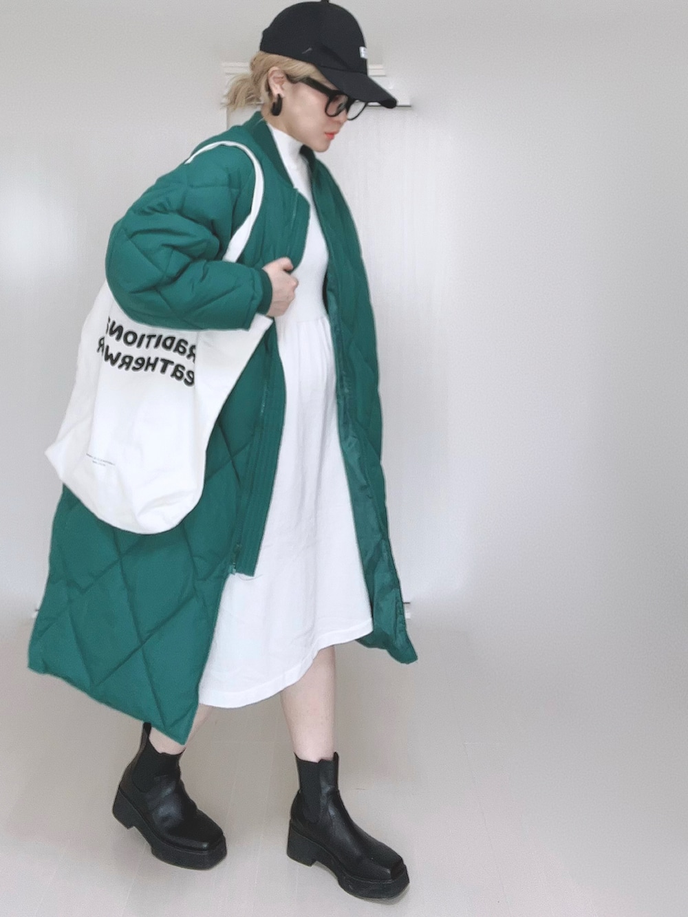 グリーン系のダウンジャケット/コート、ホワイト系のワンピース、ホワイト系のトートバッグを着用したレディースの冬コーディネートの2枚目の写真