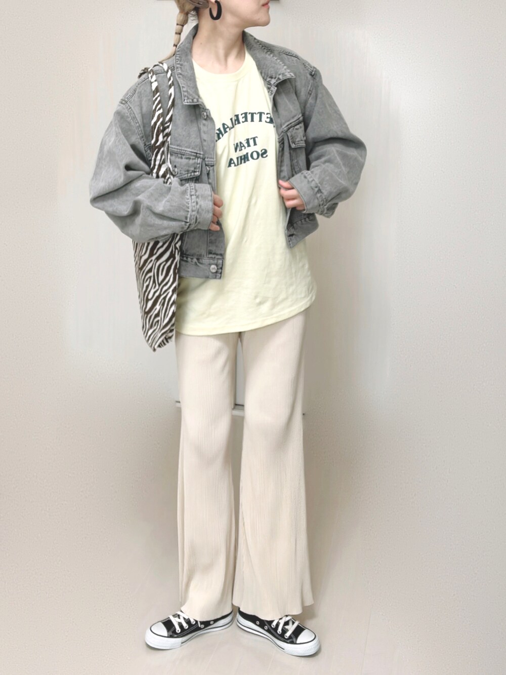イエロー系のTシャツ/カットソー、ブラック系のデニムジャケット、ホワイト系のその他パンツを着用したレディースの秋コーディネートの4枚目の写真