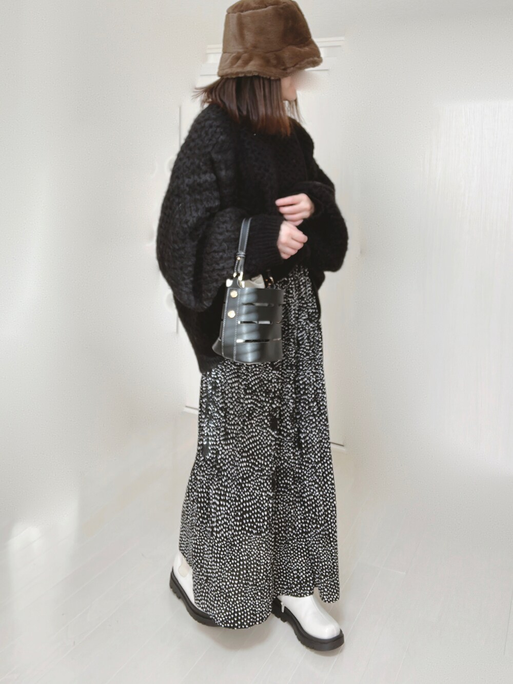 ブラック系のニット/セーター、ブラック系のショルダーバッグ、ブラック系のスカートを着用したレディースの冬コーディネートの4枚目の写真