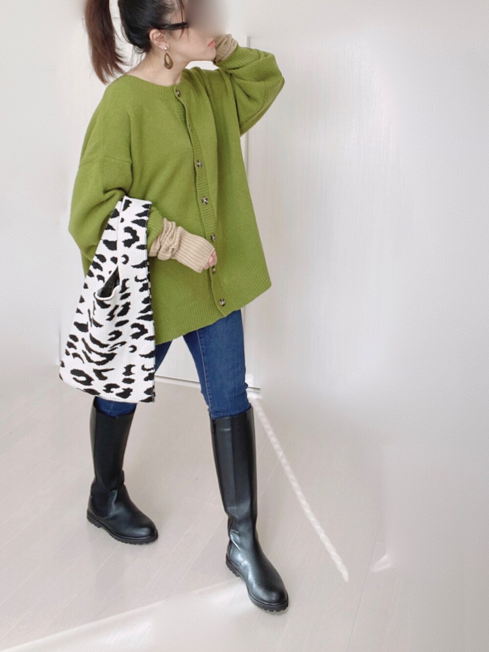 グリーン系のカーディガン/ボレロ、ブルー系のデニムパンツ、ブラック系のブーツを着用したレディースの秋コーディネートの2枚目の写真