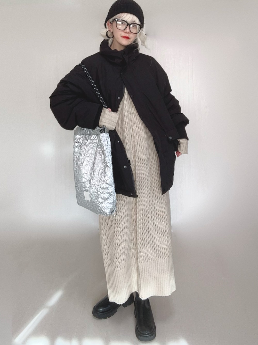 ブラック系のブルゾン、ホワイト系のワンピース、シルバー系のトートバッグを着用したレディースの冬コーディネートの3枚目の写真