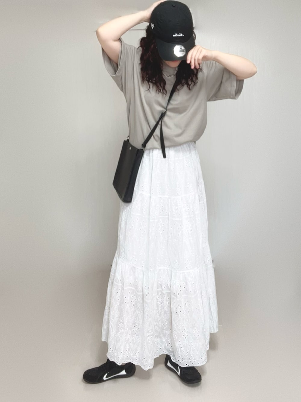 ブラック系のショルダーバッグ、ベージュ系のTシャツ/カットソー、ホワイト系のスカートを着用したレディースの夏コーディネートの3枚目の写真