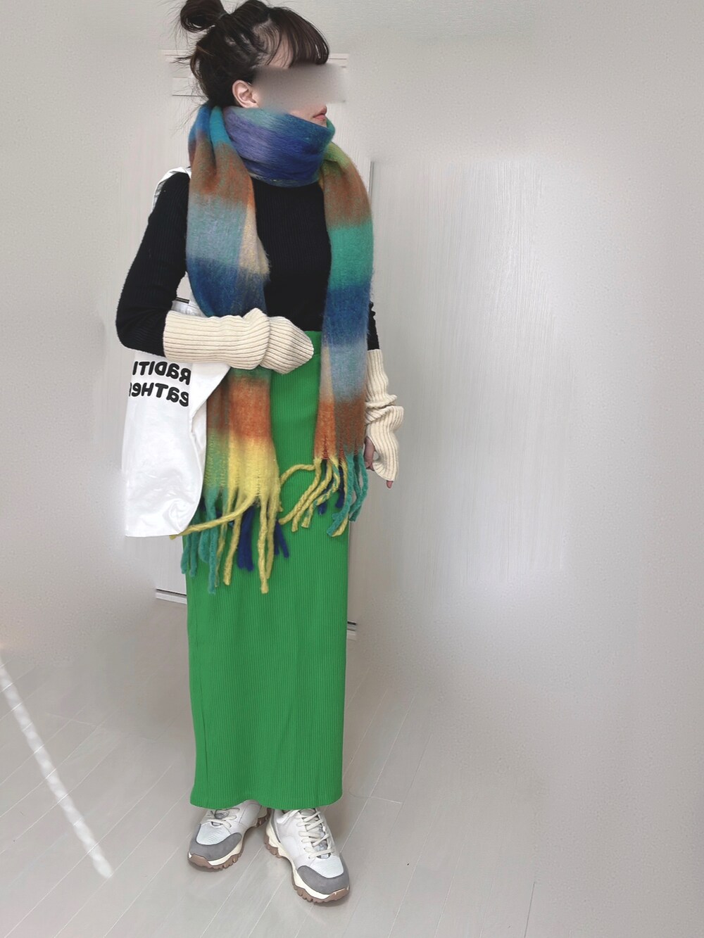 ホワイト系のトートバッグ、グリーン系のスカート、ベージュ系のスニーカーを着用したレディースの冬コーディネートの2枚目の写真