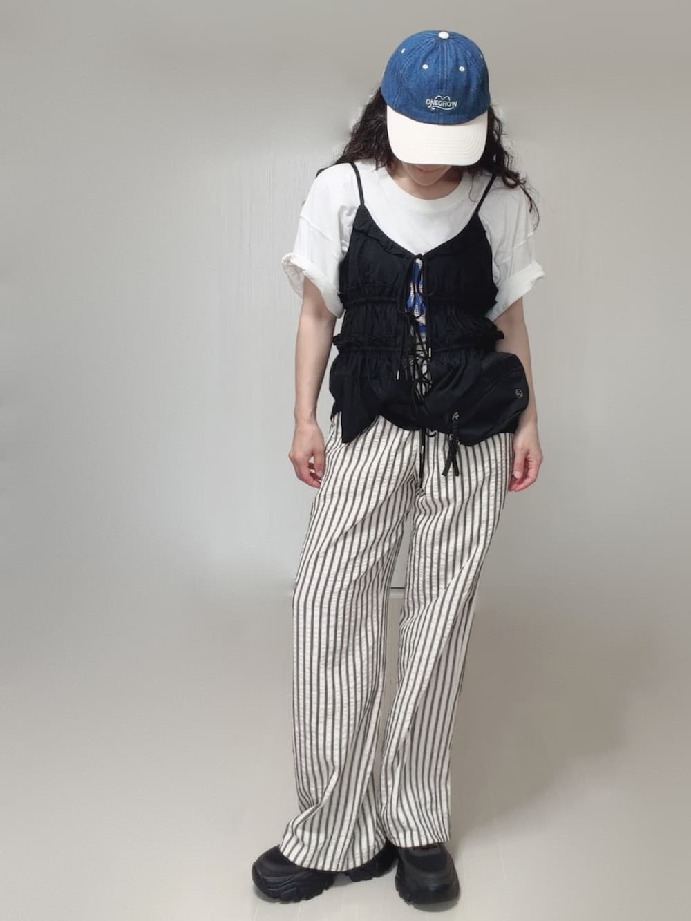 ブラック系のキャミソール、ブラック系のボディバッグ/ウエストポーチ、ホワイト系のTシャツ/カットソーを着用したレディースの夏コーディネートの5枚目の写真