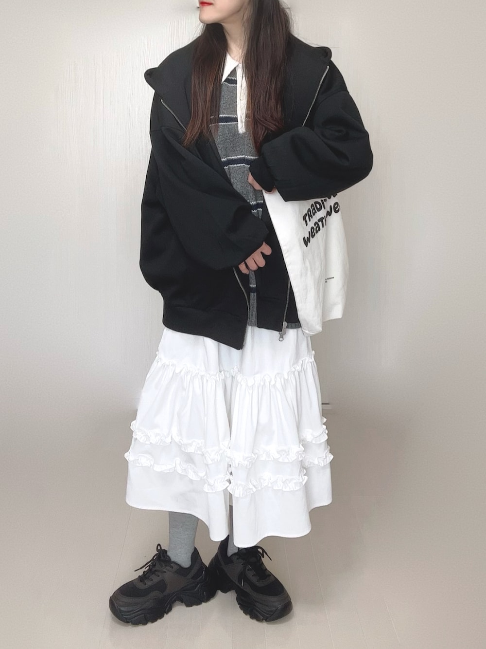 ブラック系のパーカー、グレー系のニット/セーター、ホワイト系のスカートを着用したレディースの春コーディネートの5枚目の写真