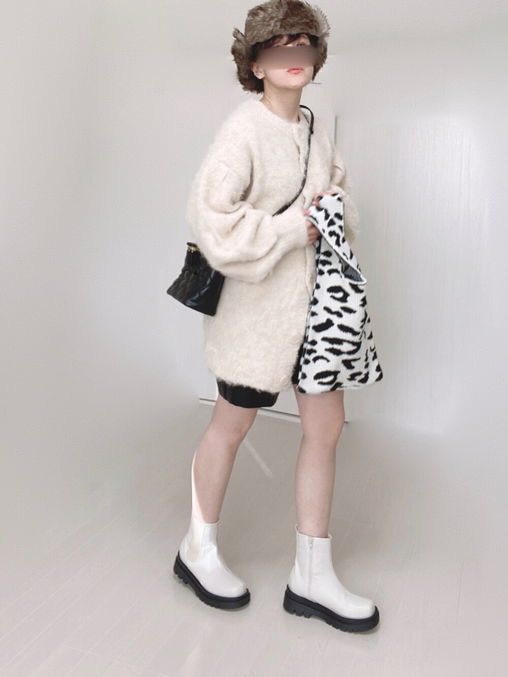 ホワイト系のブーツ、ベージュ系のカーディガン/ボレロ、ブラック系のショルダーバッグを着用したレディースの冬コーディネートの2枚目の写真