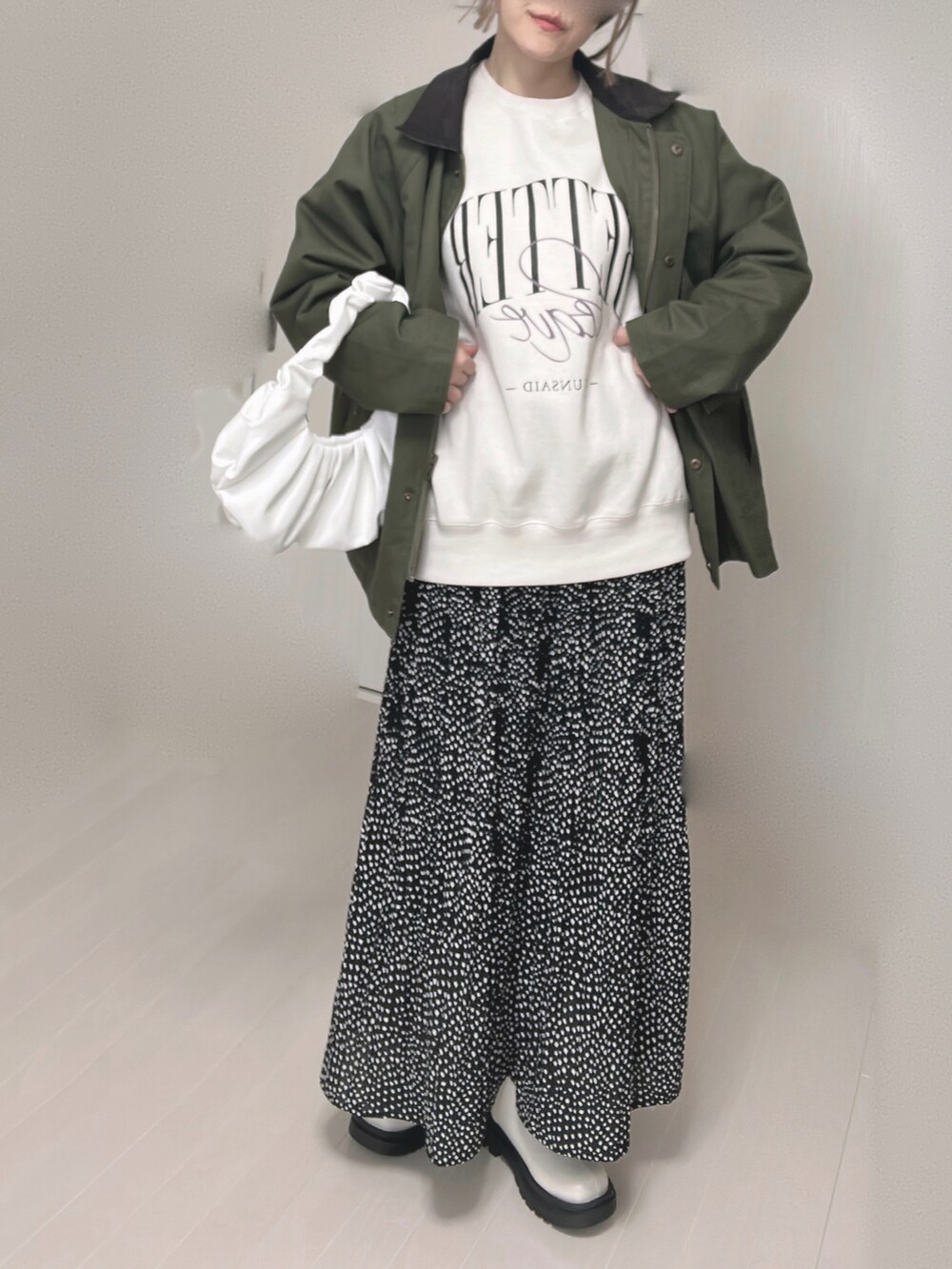 グリーン系のカバーオール、ブラック系のスカート、ホワイト系のブーツを着用したレディースの冬コーディネートの3枚目の写真