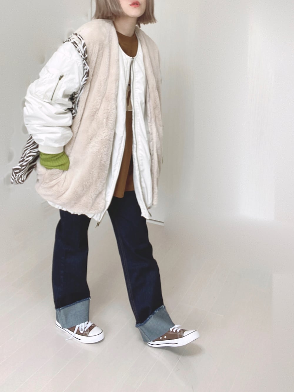 ホワイト系のブルゾン、ブラウン系のTシャツ/カットソー、ブルー系のデニムパンツを着用したレディースの秋コーディネートの5枚目の写真