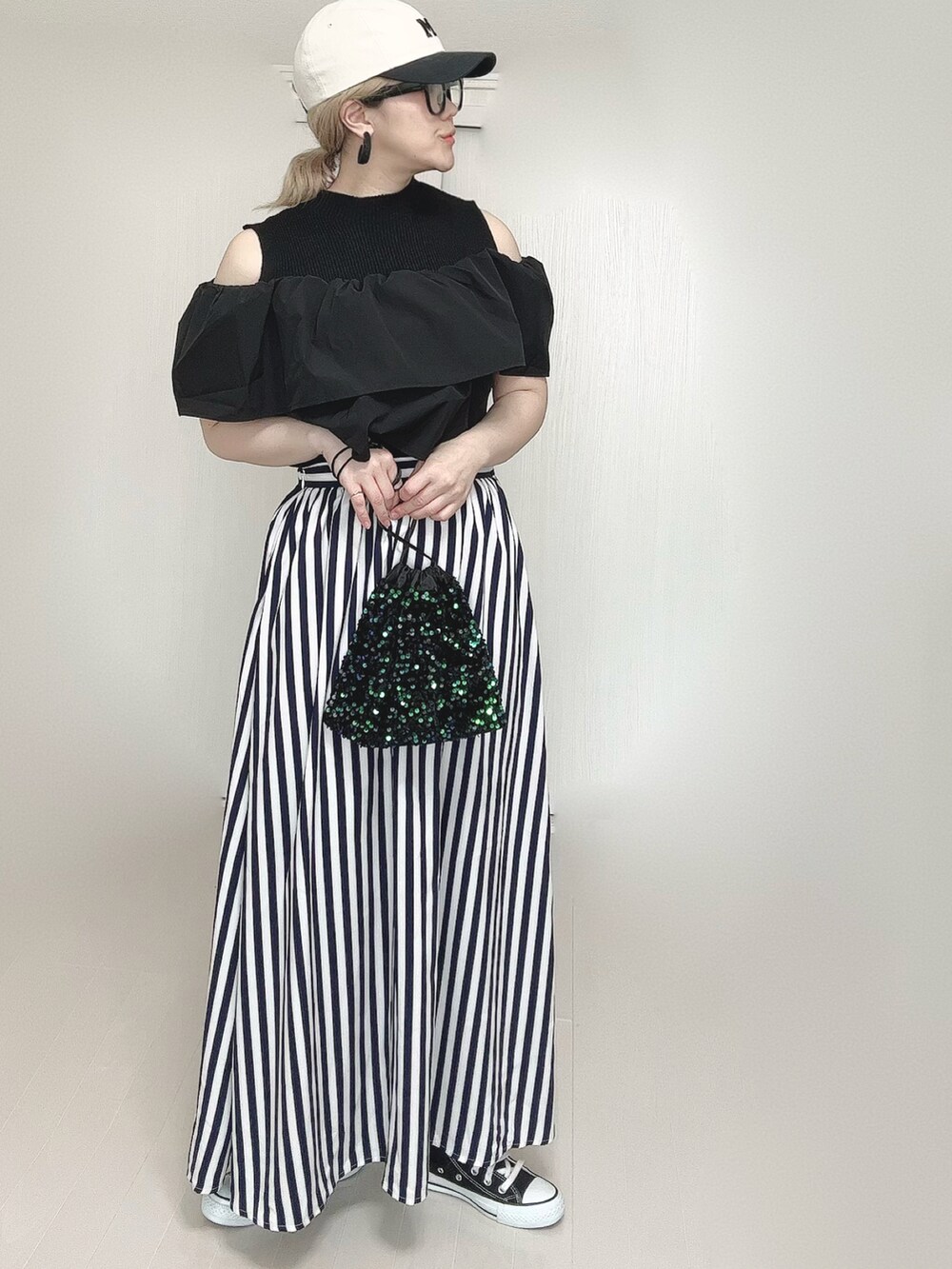 ブルー系のスカート、ブラック系のスニーカー、ブラック系のキャップを着用したレディースの春コーディネートの4枚目の写真