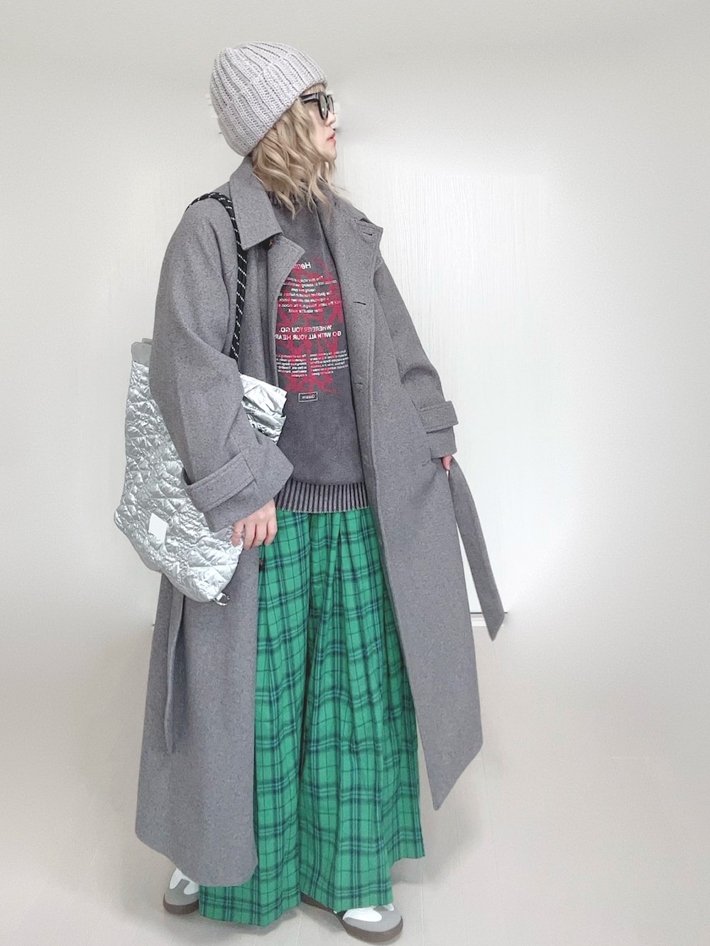 ブラック系のニット/セーター、グレー系のステンカラーコート、シルバー系のトートバッグを着用したレディースの春コーディネートの2枚目の写真