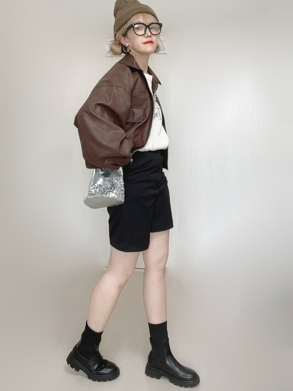 ブラウン系のブルゾン、ホワイト系のニット/セーター、ブラック系のブーツを着用したレディースの秋コーディネートの2枚目の写真