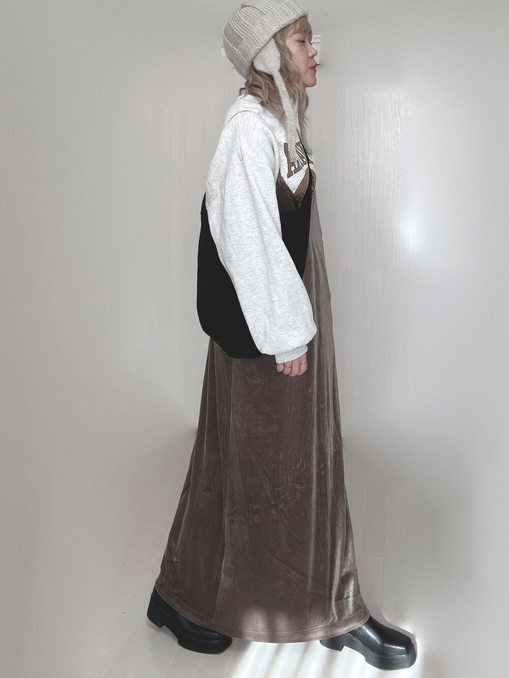 ブラウン系のワンピース、ホワイト系のTシャツ/カットソー、ブラック系のブーツを着用したレディースの秋コーディネートの2枚目の写真