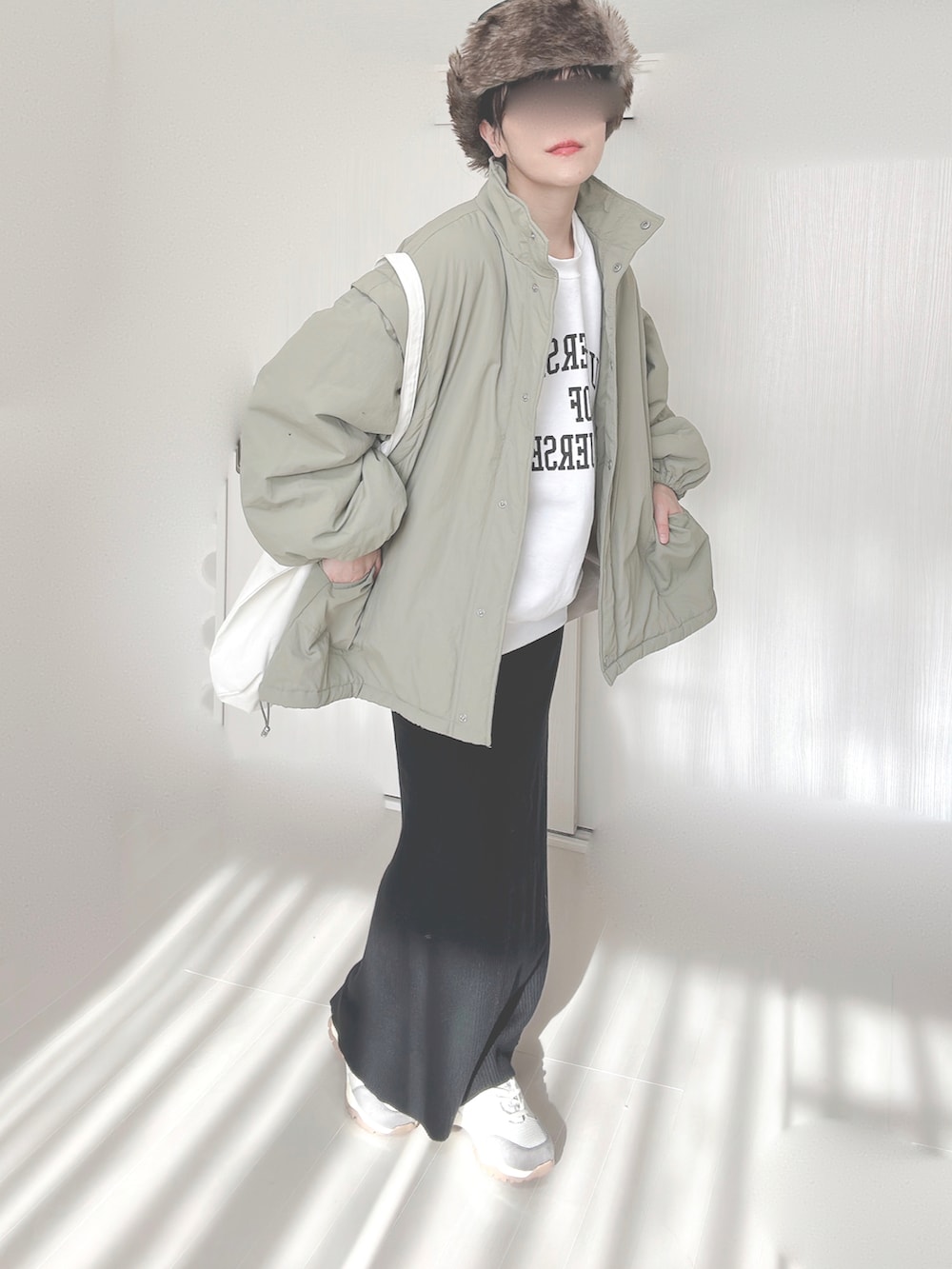 ホワイト系のスウェット、グリーン系のダウンジャケット/コート、ブラック系のスカートを着用したレディースの冬コーディネートの5枚目の写真