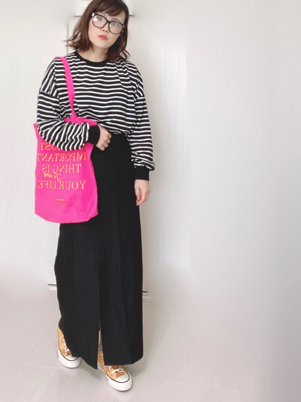 ブラック系のスカート、ホワイト系のTシャツ/カットソー、ピンク系のトートバッグを着用したレディースの秋コーディネートの3枚目の写真