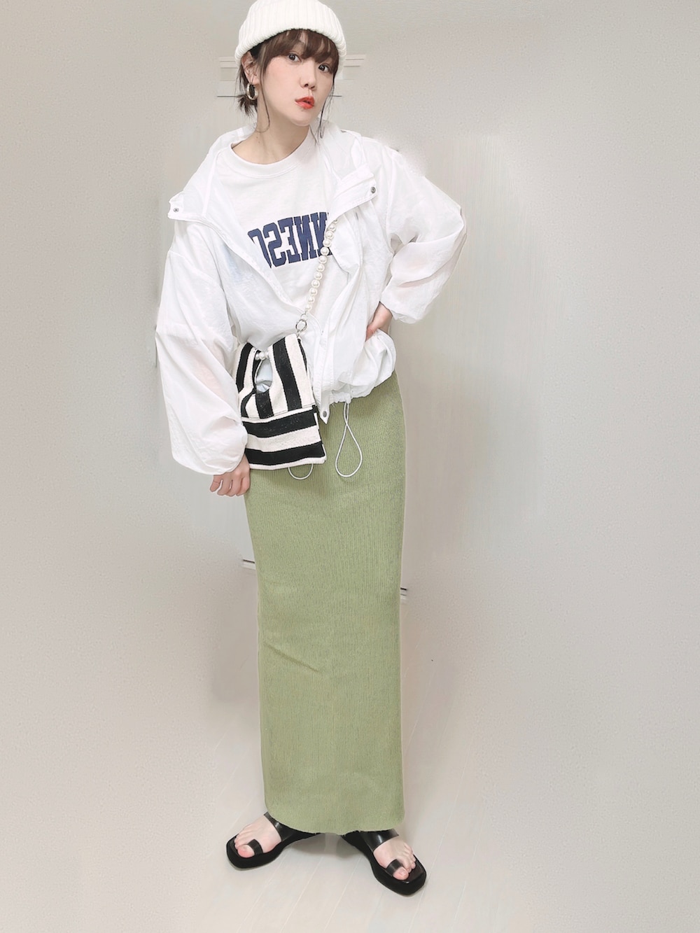 グリーン系のスカート、ホワイト系のショルダーバッグ、ブラック系のサンダルを着用したレディースの春コーディネートの4枚目の写真