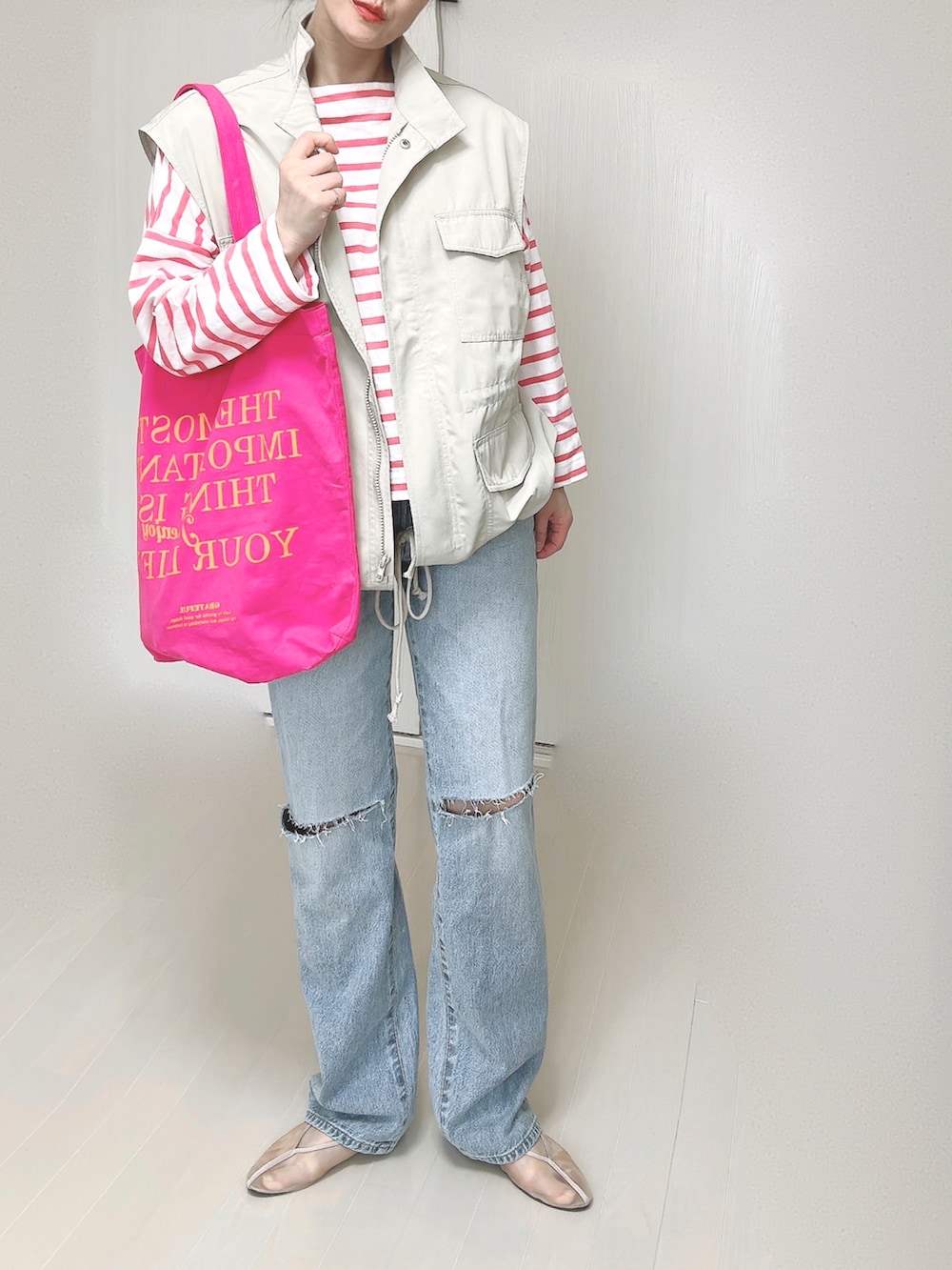 ブルー系のデニムパンツ、ホワイト系のベスト、ピンク系のTシャツ/カットソーを着用したレディースの春コーディネートの3枚目の写真