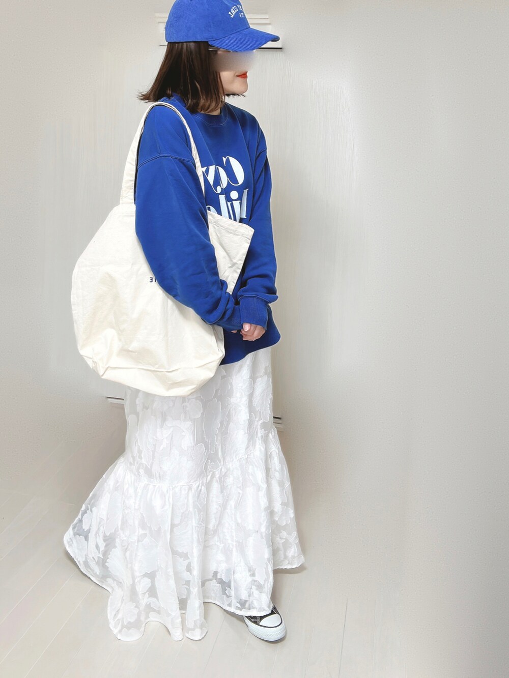 ブルー系のスウェット、ホワイト系のトートバッグ、ホワイト系のスカートを着用したレディースの春コーディネートの5枚目の写真