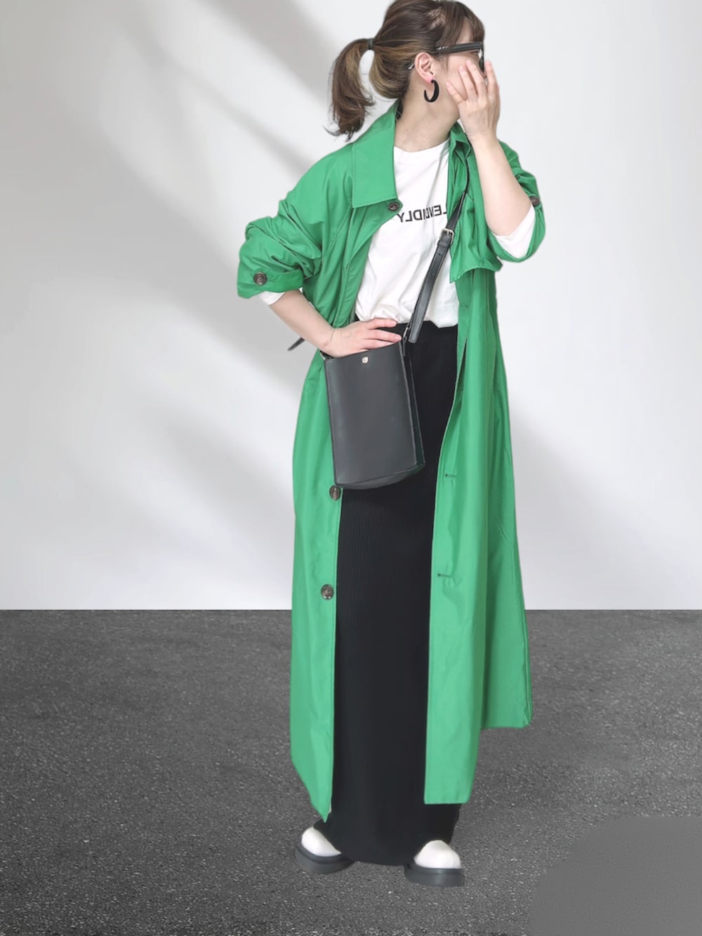 グリーン系のトレンチコート、ブラック系のショルダーバッグ、ブラック系のスカートを着用したレディースの秋コーディネートの3枚目の写真