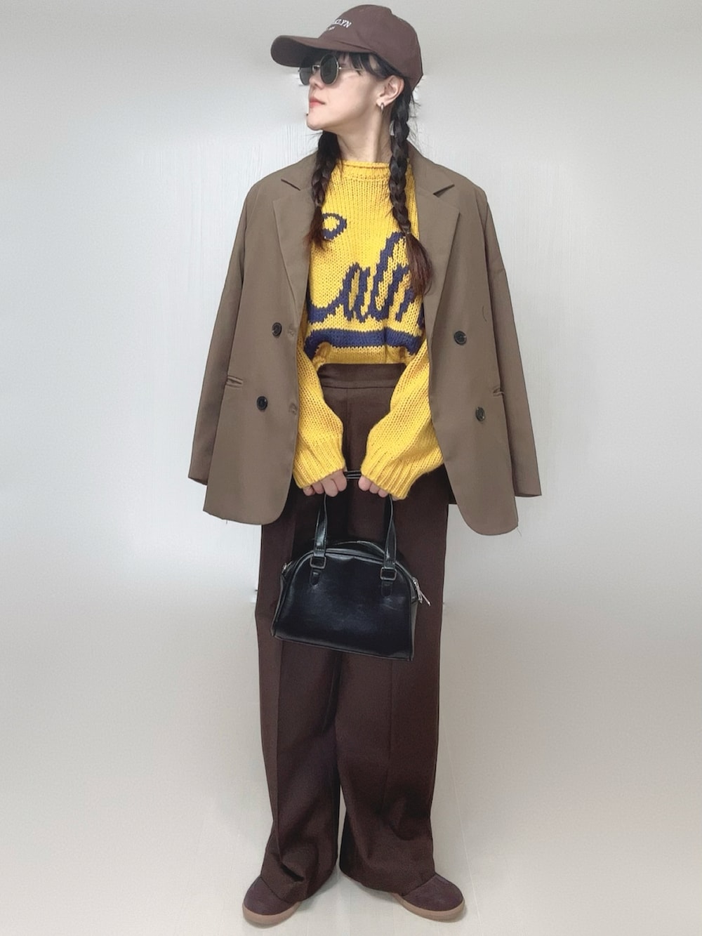 イエロー系のニット/セーター、ブラウン系のテーラードジャケット、ブラウン系のその他パンツを着用したレディースの冬コーディネートの2枚目の写真