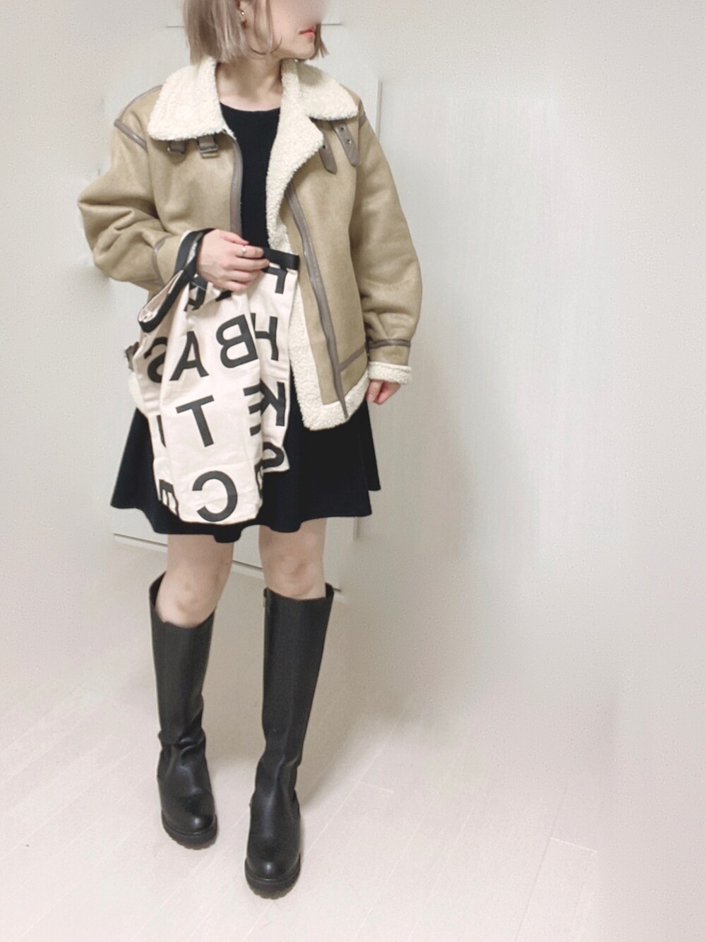 ブラック系のブーツ、ベージュ系のムートンコート、ホワイト系のトートバッグを着用したレディースの秋コーディネートの3枚目の写真