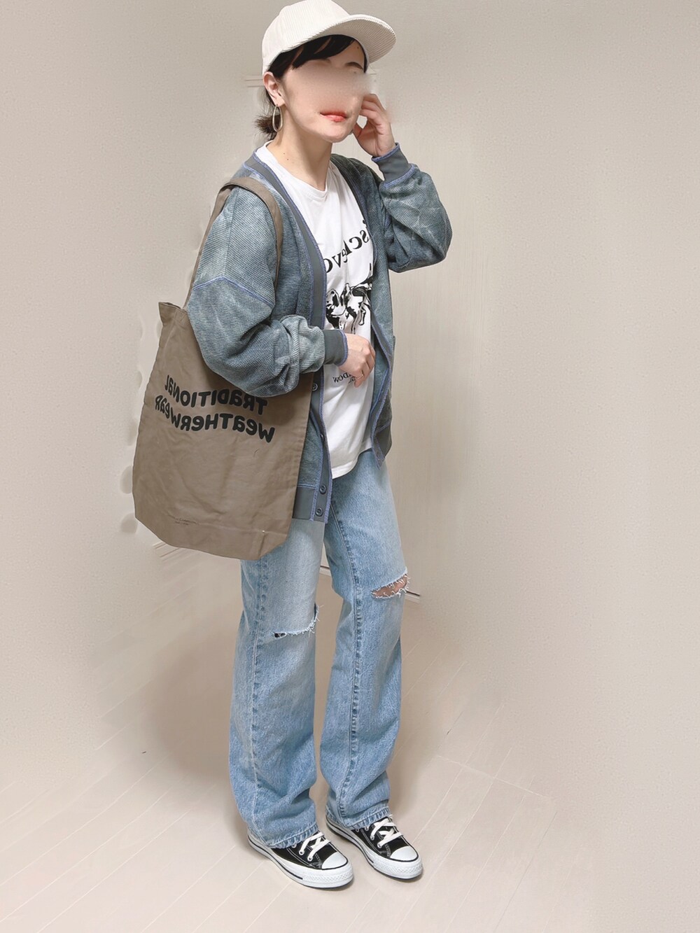 ブルー系のデニムパンツ、ブラック系のカーディガン/ボレロ、ブラウン系のトートバッグを着用したレディースの春コーディネートの3枚目の写真