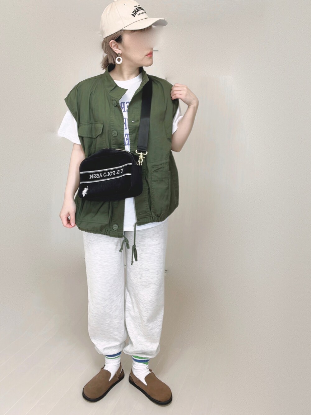 ブラック系のショルダーバッグ、ホワイト系のTシャツ/カットソー、ブラウン系のスリッポンを着用したレディースの春コーディネートの3枚目の写真