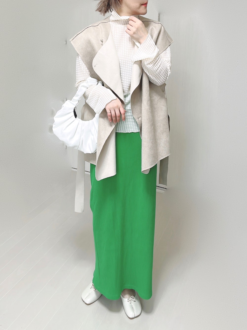 ホワイト系のTシャツ/カットソー、ベージュ系のベスト、グリーン系のスカートを着用したレディースの春コーディネートの3枚目の写真