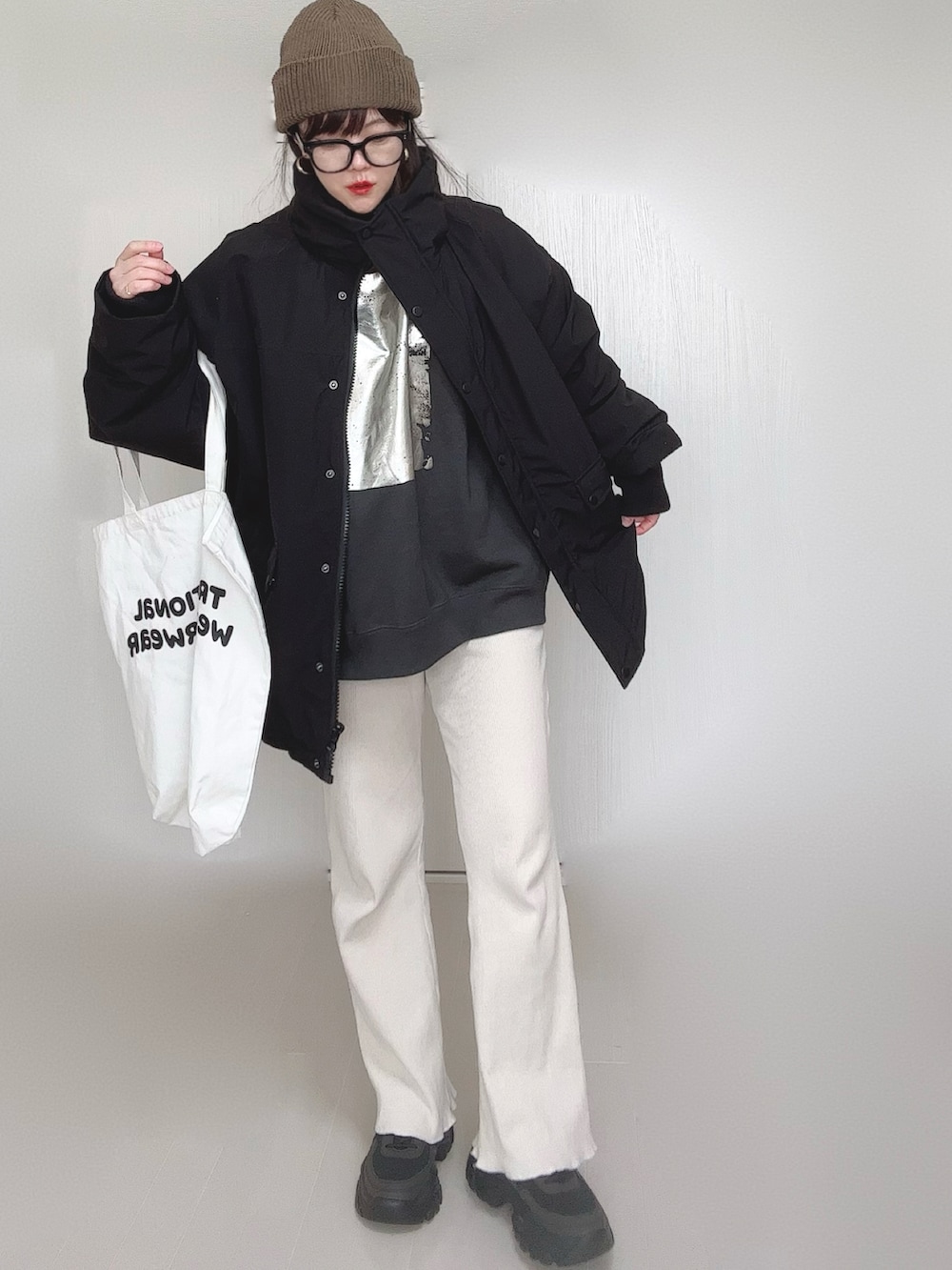 ブラック系のブルゾン、ブラック系のスウェット、ホワイト系のトートバッグを着用したレディースの冬コーディネートの3枚目の写真