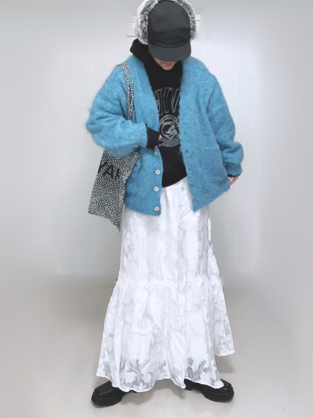 ブラック系のパーカー、ホワイト系のスカート、ブラック系のブーツを着用したレディースの冬コーディネートの4枚目の写真