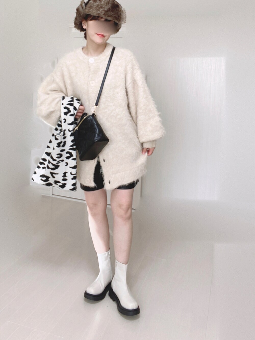 ホワイト系のブーツ、ベージュ系のカーディガン/ボレロ、ブラック系のショルダーバッグを着用したレディースの冬コーディネートの3枚目の写真