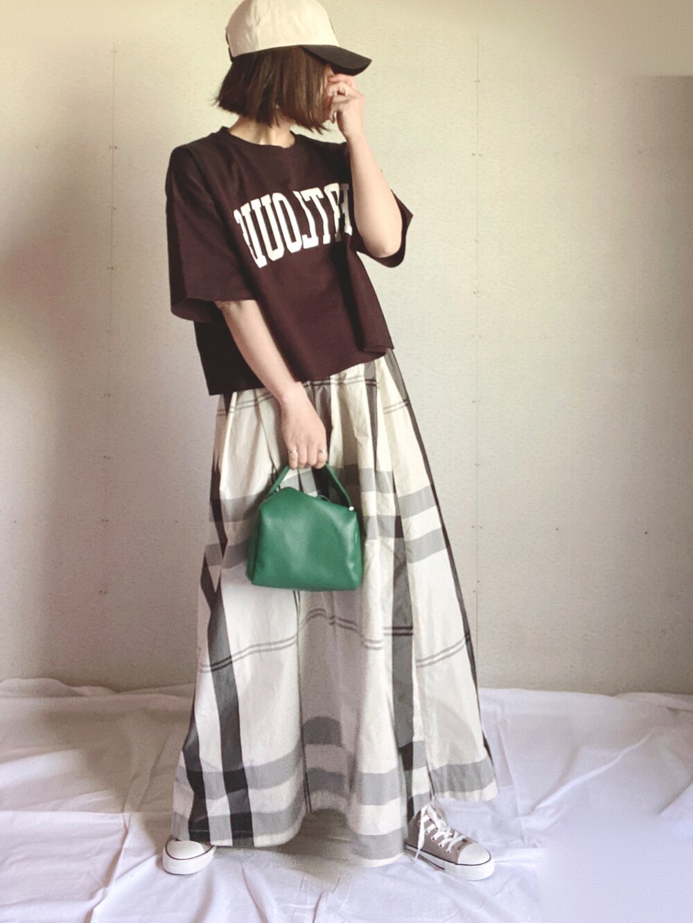 ホワイト系のスカート、ブラック系のTシャツ/カットソー、グリーン系のハンドバッグを着用したレディースの夏コーディネートの2枚目の写真