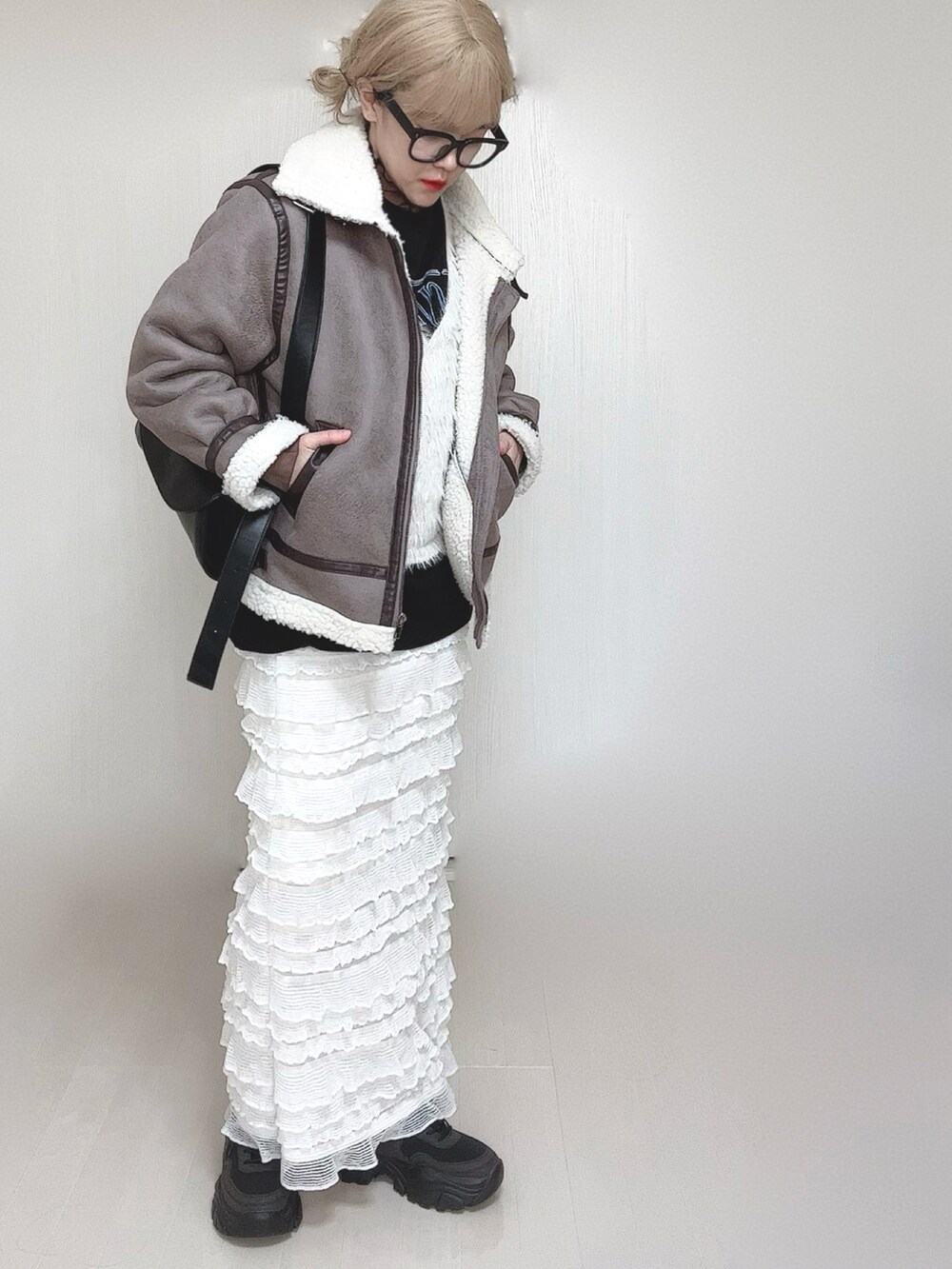 グレー系のムートンコート、ホワイト系のベスト、ブラック系のTシャツ/カットソーを着用したレディースの冬コーディネートの3枚目の写真