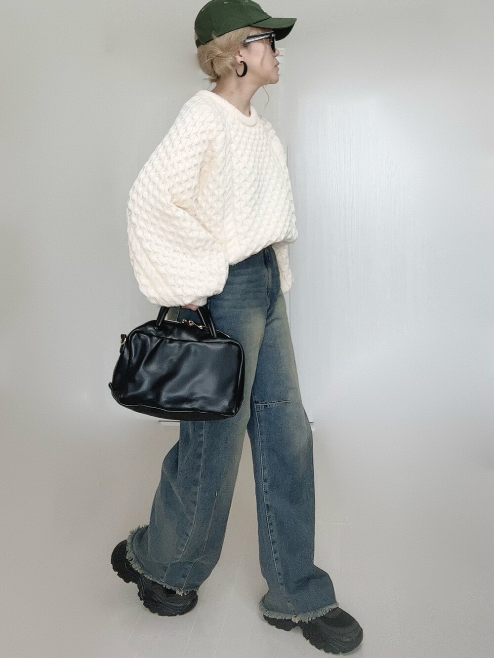 ブルー系のデニムパンツ、ホワイト系のニット/セーター、ブラック系のボストンバッグを着用したレディースの秋コーディネートの2枚目の写真