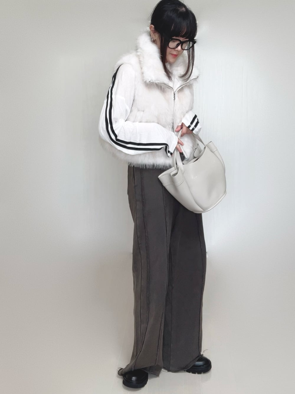 ホワイト系のベスト、ブラック系のブーツ、ホワイト系のTシャツ/カットソーを着用したレディースの秋コーディネートの3枚目の写真