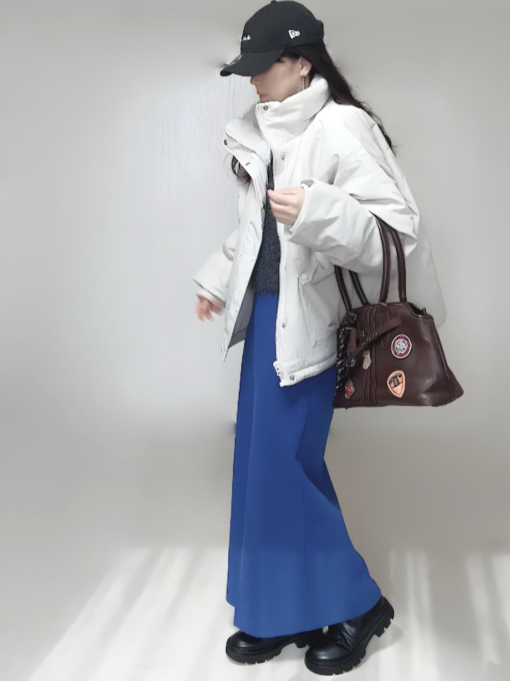 ホワイト系のブルゾン、ブラック系のブーツ、グレー系のベストを着用したレディースの秋コーディネートの4枚目の写真