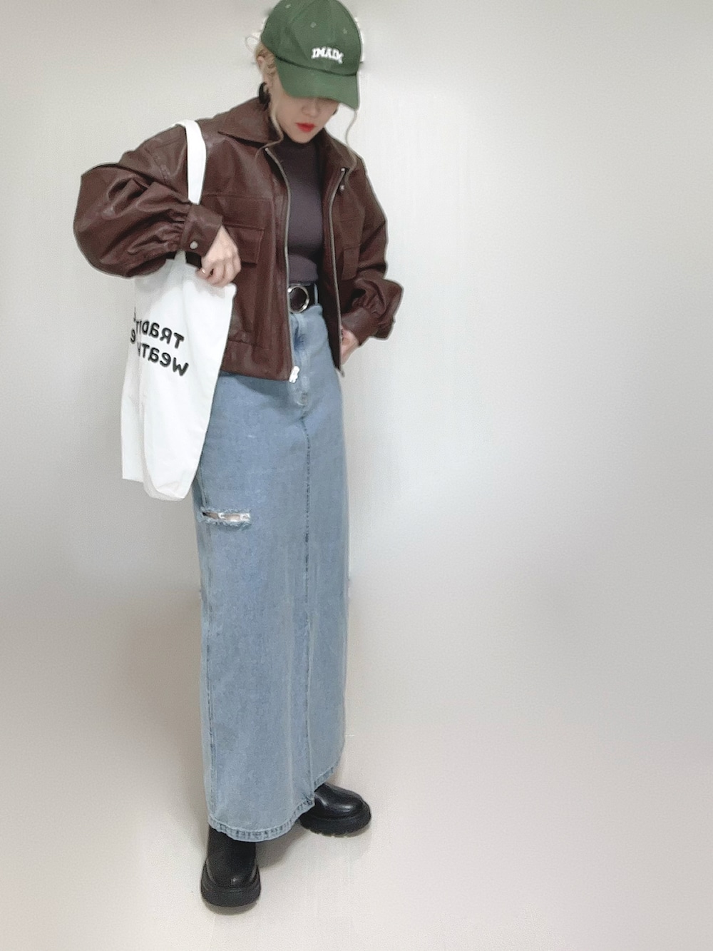 ブラウン系のブルゾン、ホワイト系のトートバッグ、ブラック系のブーツを着用したレディースの秋コーディネートの3枚目の写真