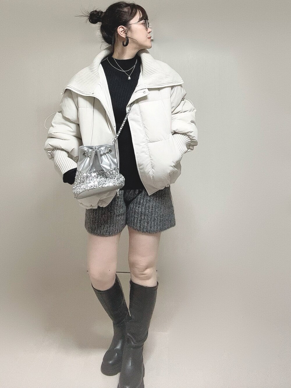 ホワイト系のダウンジャケット/コート、ブラック系のニット/セーター、ブラック系のブーツを着用したレディースの冬コーディネートの3枚目の写真