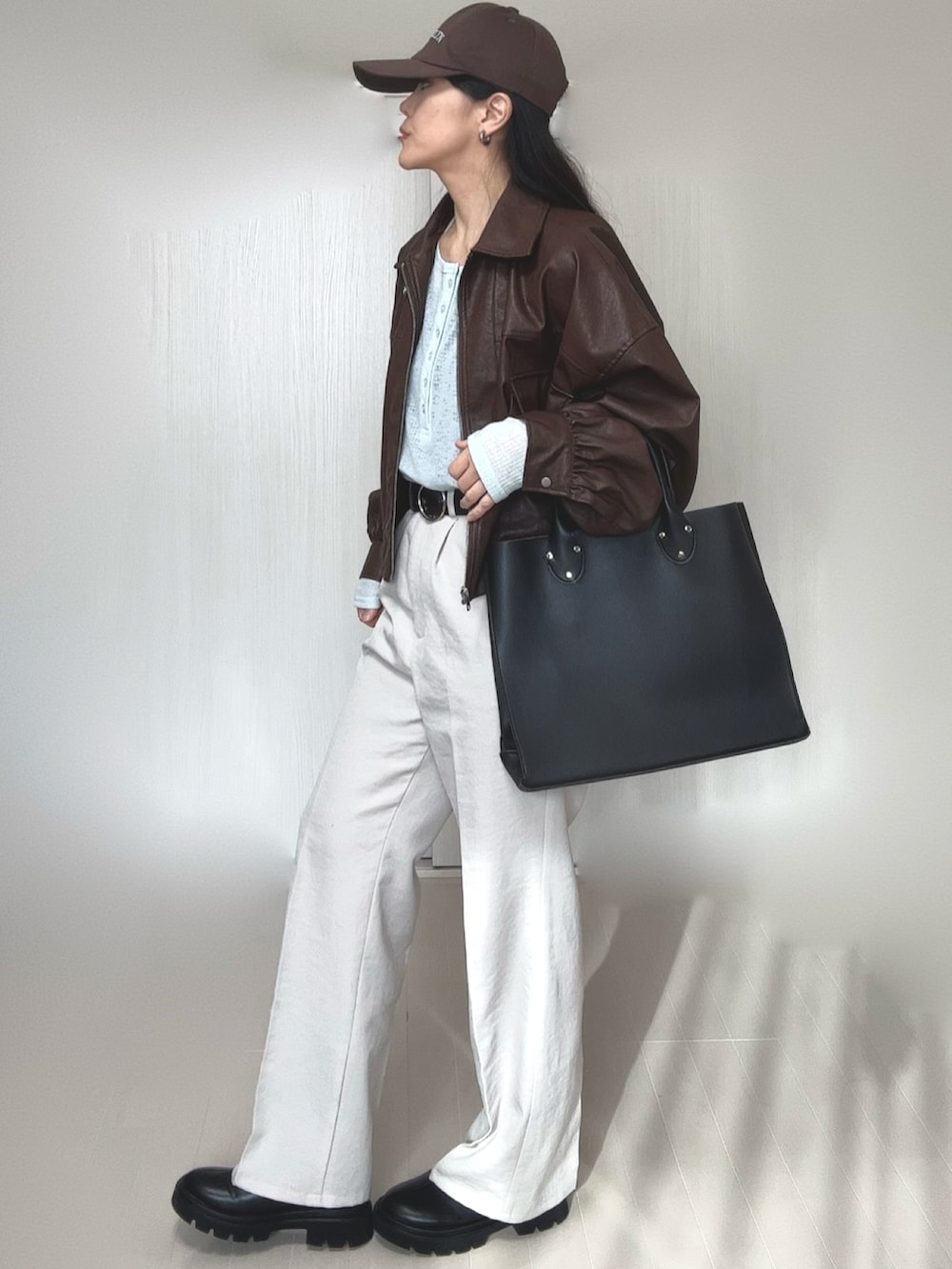 ブルー系のTシャツ/カットソー、ブラウン系のブルゾン、ブラック系のトートバッグを着用したレディースの冬コーディネートの3枚目の写真