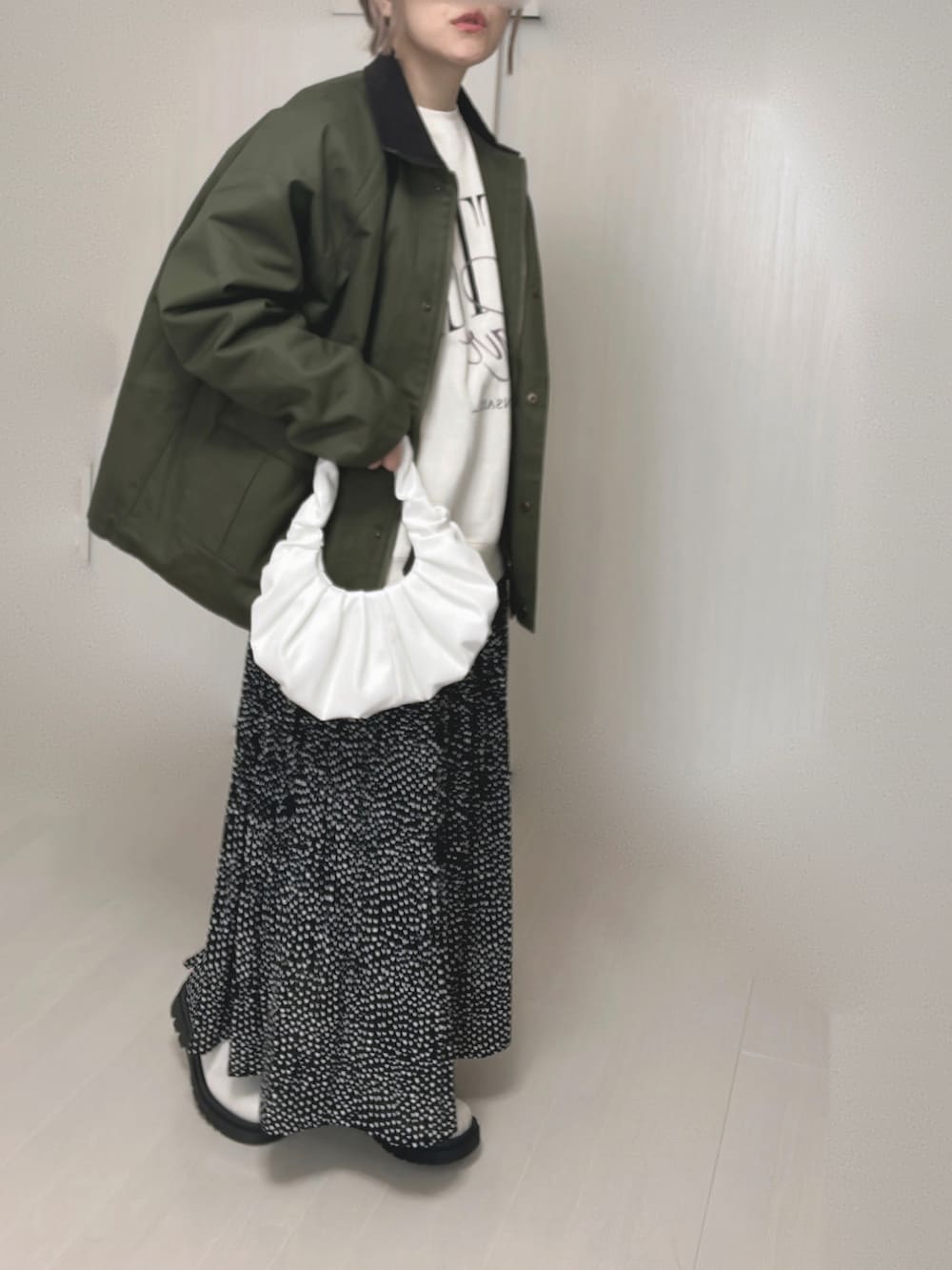 グリーン系のカバーオール、ブラック系のスカート、ホワイト系のブーツを着用したレディースの冬コーディネートの2枚目の写真