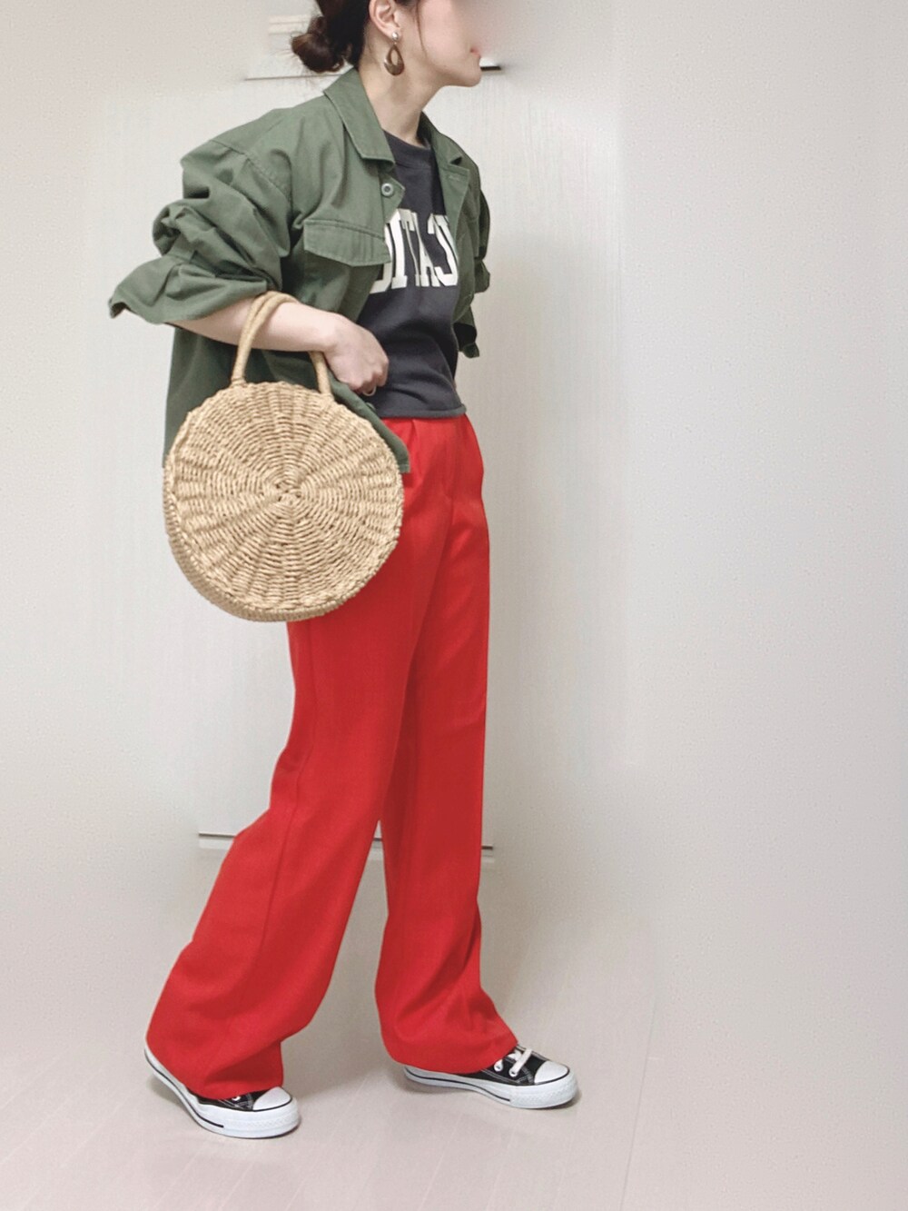 ベージュ系のかごバッグ、グリーン系のミリタリージャケット、ブラック系のスニーカーを着用したレディースの春コーディネートの4枚目の写真