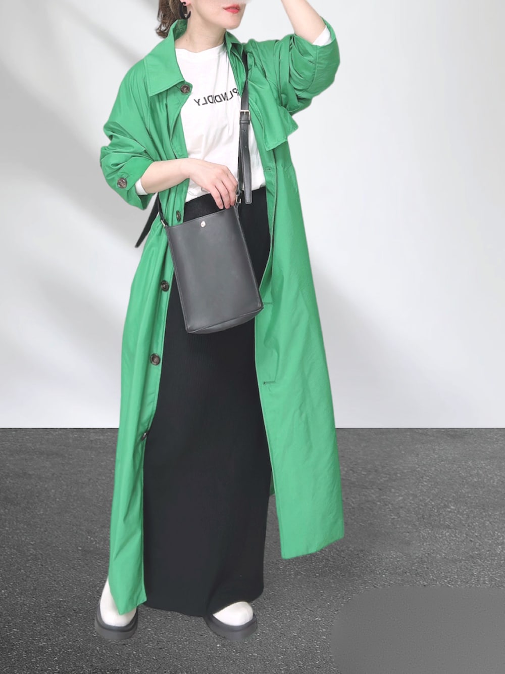 グリーン系のトレンチコート、ブラック系のショルダーバッグ、ブラック系のスカートを着用したレディースの秋コーディネートの5枚目の写真