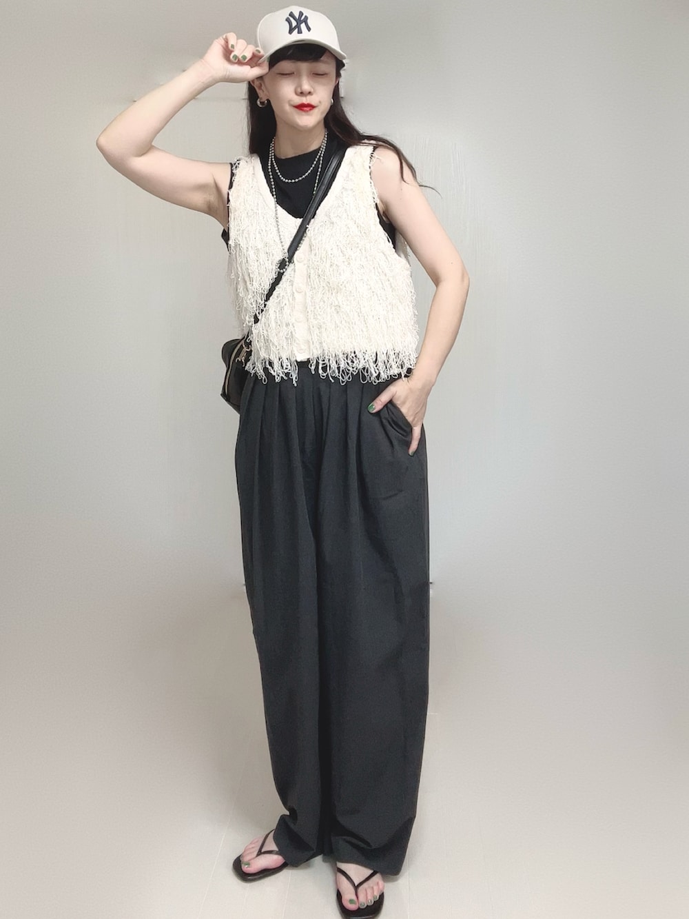 ホワイト系のベスト、グレー系のスラックス、ブラック系のボストンバッグを着用したレディースの夏コーディネートの4枚目の写真