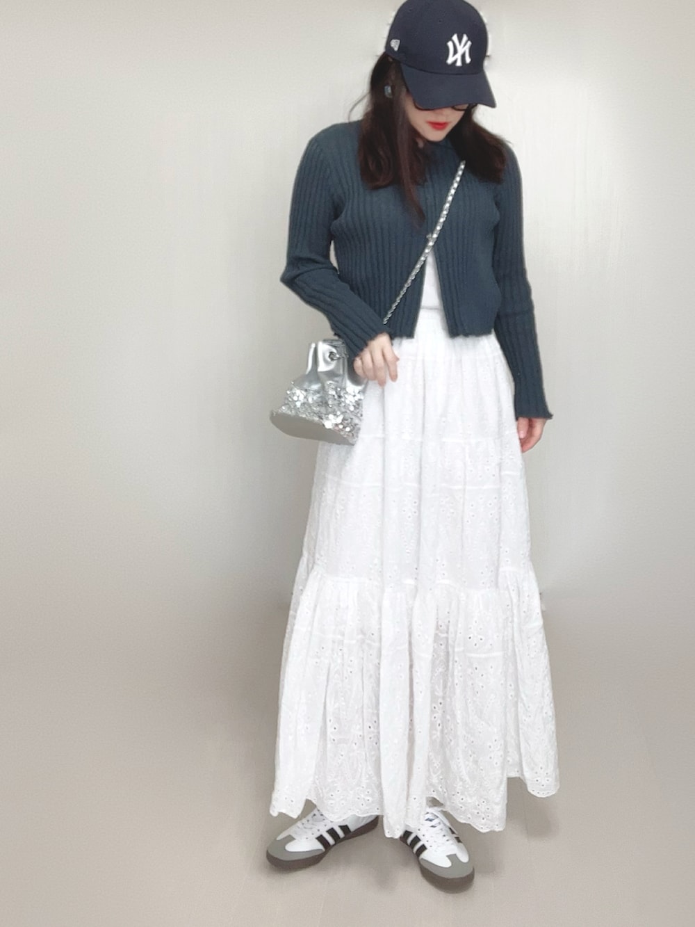 グレー系のカーディガン/ボレロ、シルバー系のショルダーバッグ、ホワイト系のスカートを着用したレディースの春コーディネートの3枚目の写真