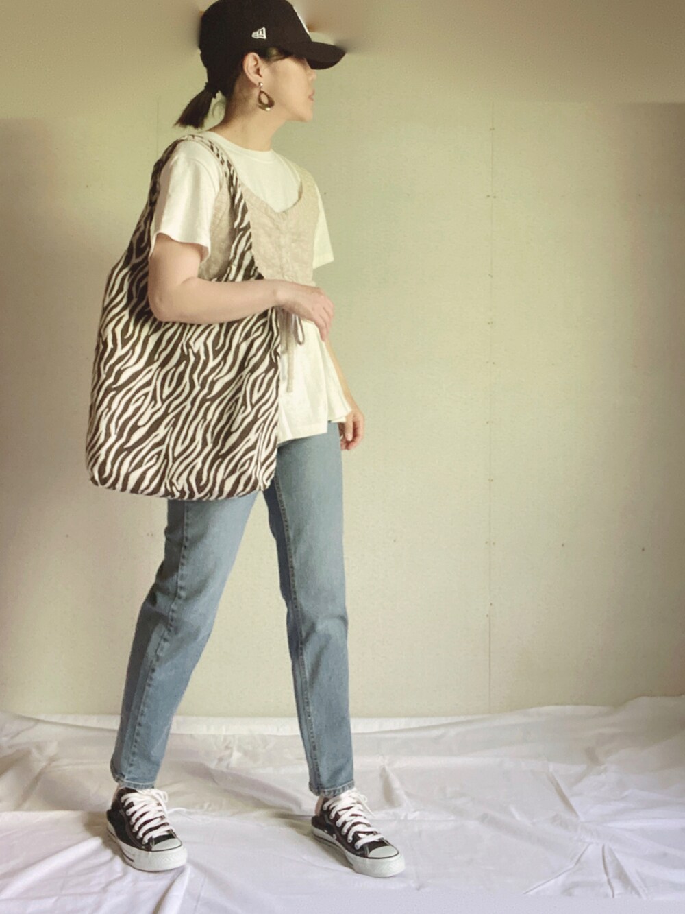 ブルー系のデニムパンツ、ホワイト系のTシャツ/カットソー、ベージュ系のベストを着用したレディースの夏コーディネートの2枚目の写真