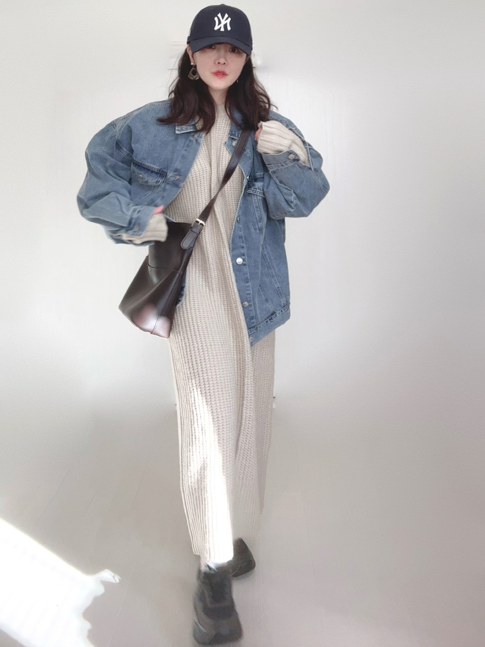 ブルー系のデニムジャケット、ホワイト系のワンピース、ブラック系のスニーカーを着用したレディースの冬コーディネートの3枚目の写真