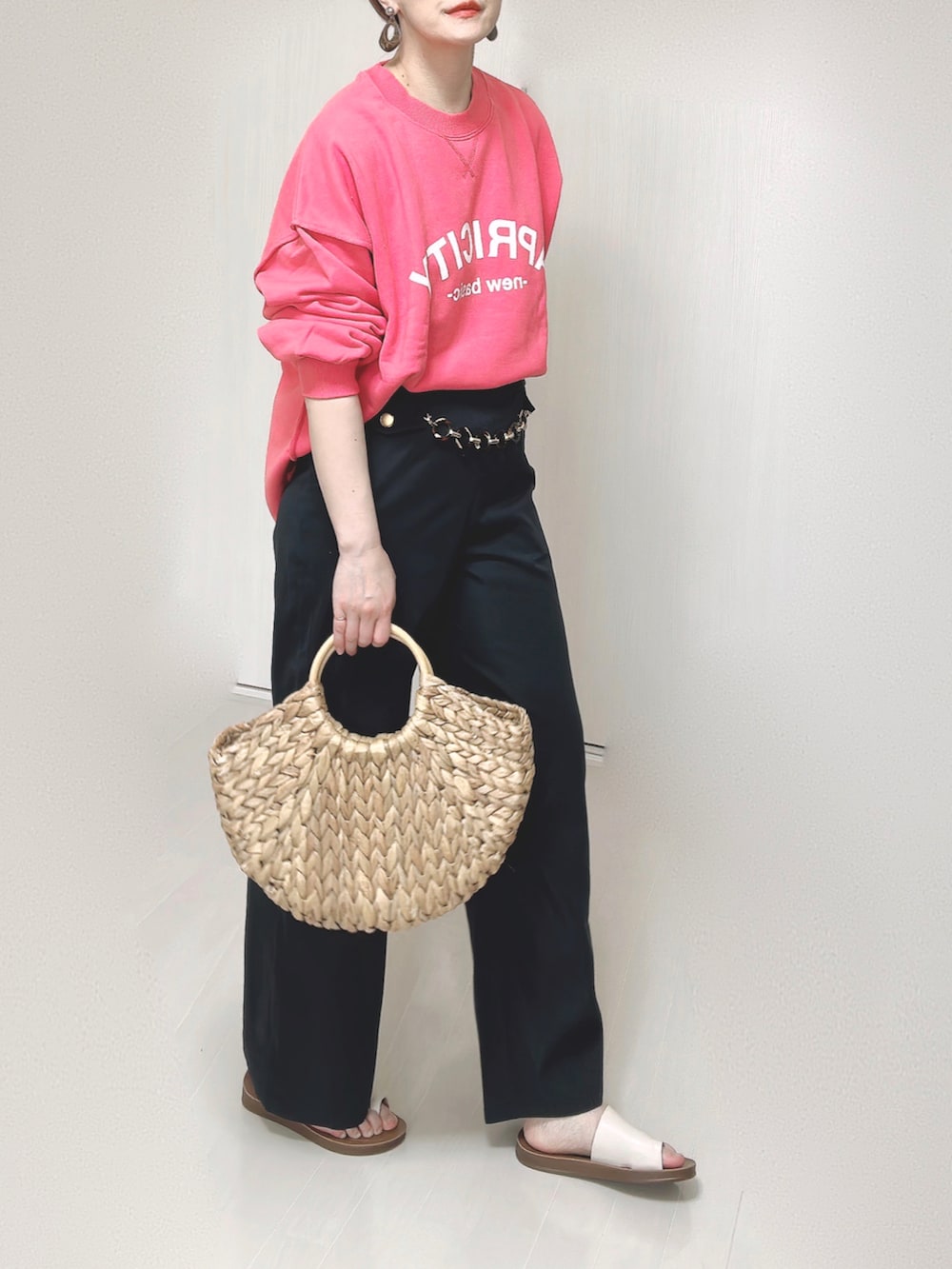 ピンク系のスウェット、ブルー系のスラックス、ベージュ系のかごバッグを着用したレディースの春コーディネートの5枚目の写真