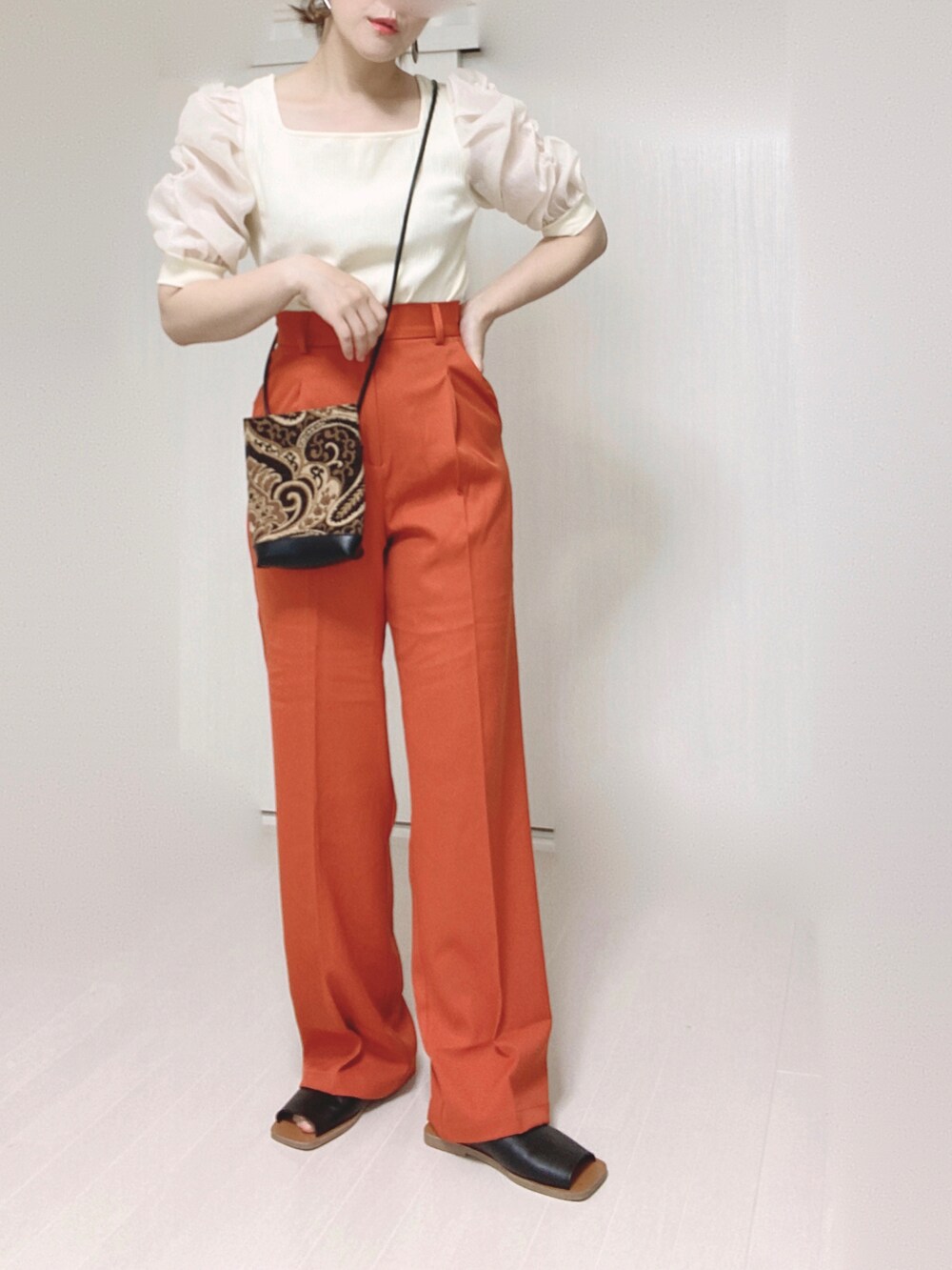 オレンジ系のスラックス、ホワイト系のTシャツ/カットソー、ブラック系のショルダーバッグを着用したレディースの夏コーディネートの5枚目の写真